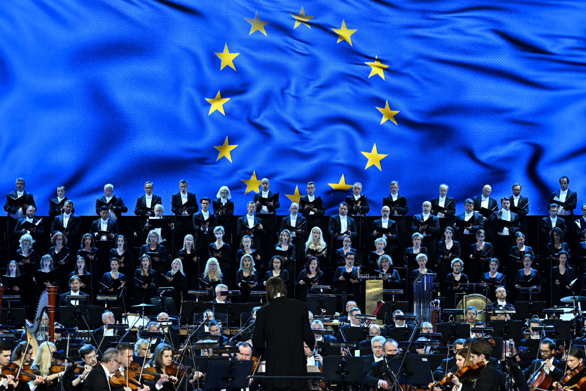 a choir on stage, the background is UE flag